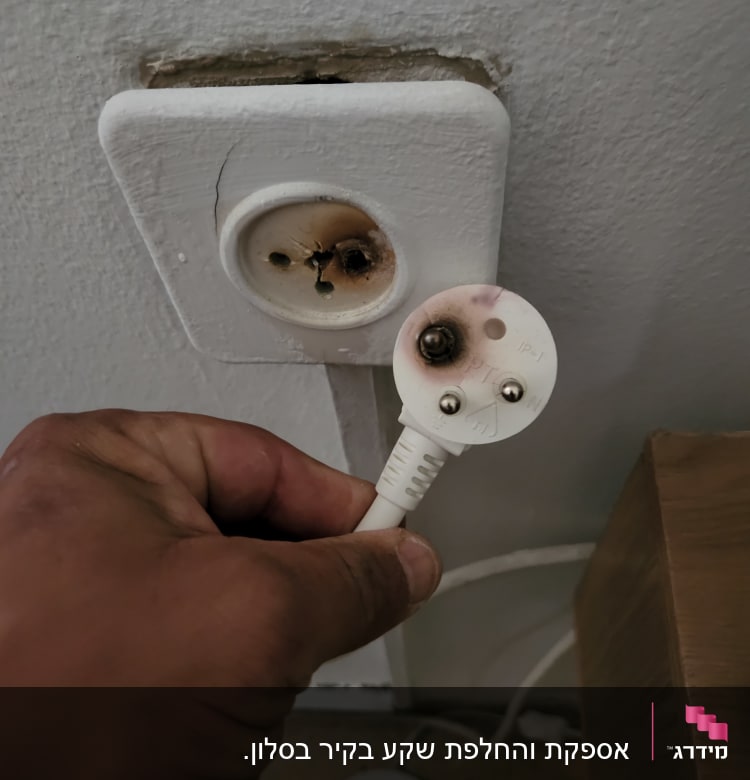 תקע חשמלי שרוף ושקע פגום על קיר